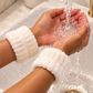 Cream wrist cuffs catching water at the faucet